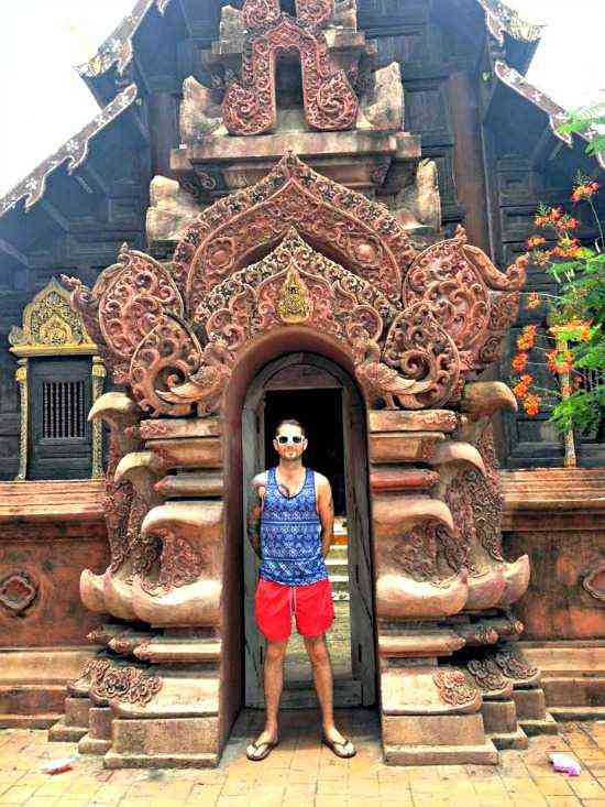 Man standing framed by front entry of temple in Chiang Mai Thailand