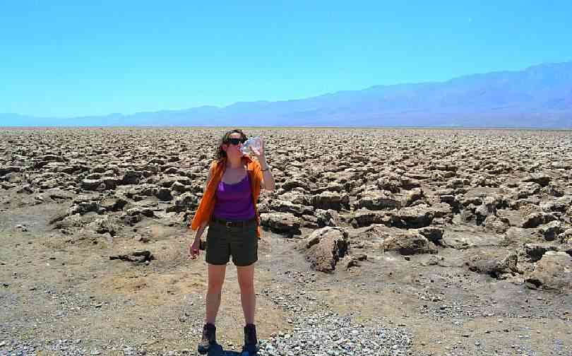 Woman standing in Death Valley desert with water bottl