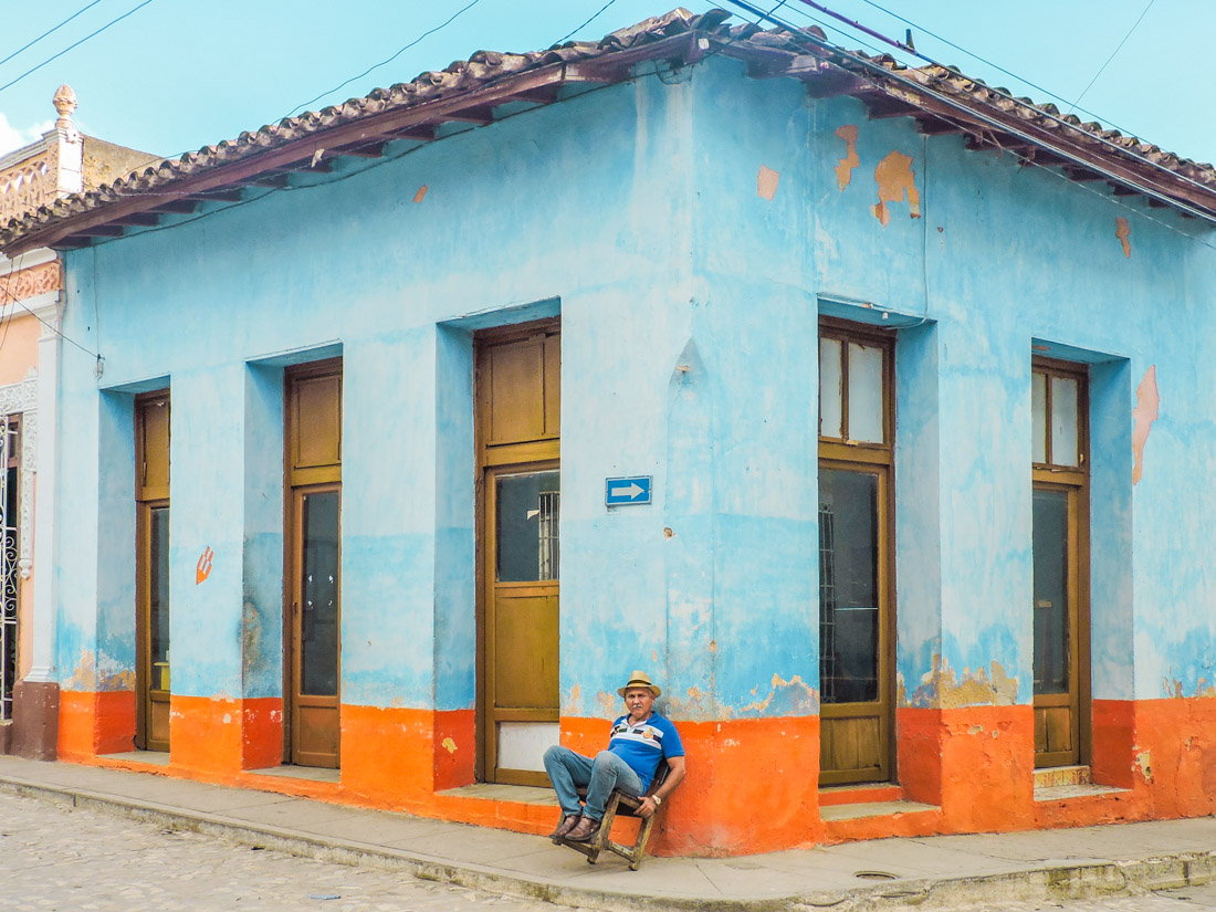 Man sitting outside a blue building in Trinidad, Cuba