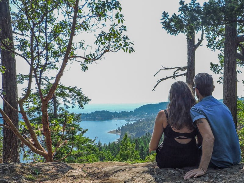 Couple sitting with back to camera at Soames Hill with views over Gibsons BC Sunshine Coast