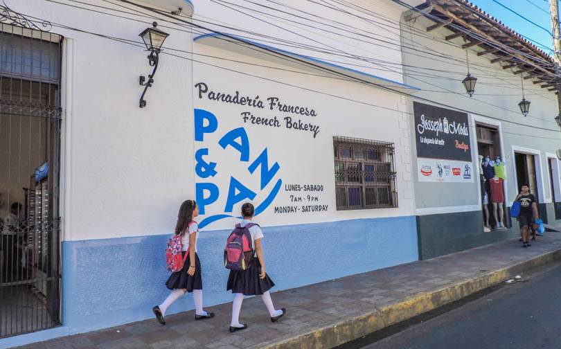 School girls walk by Pan y Paz bakery, Leon in Nicaragua 