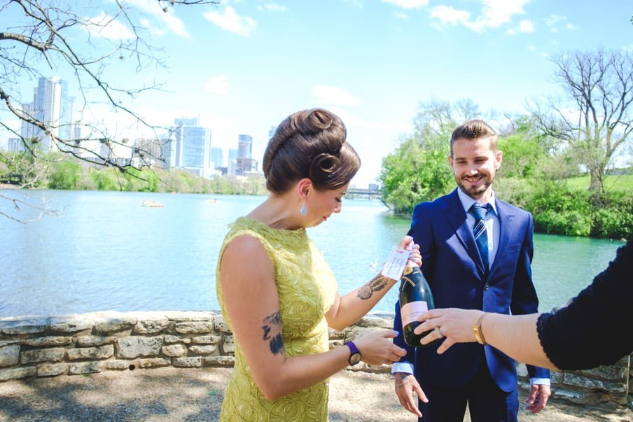 Bride and groom looking at champagne bottle at Lou Neff Point Austin elopement 