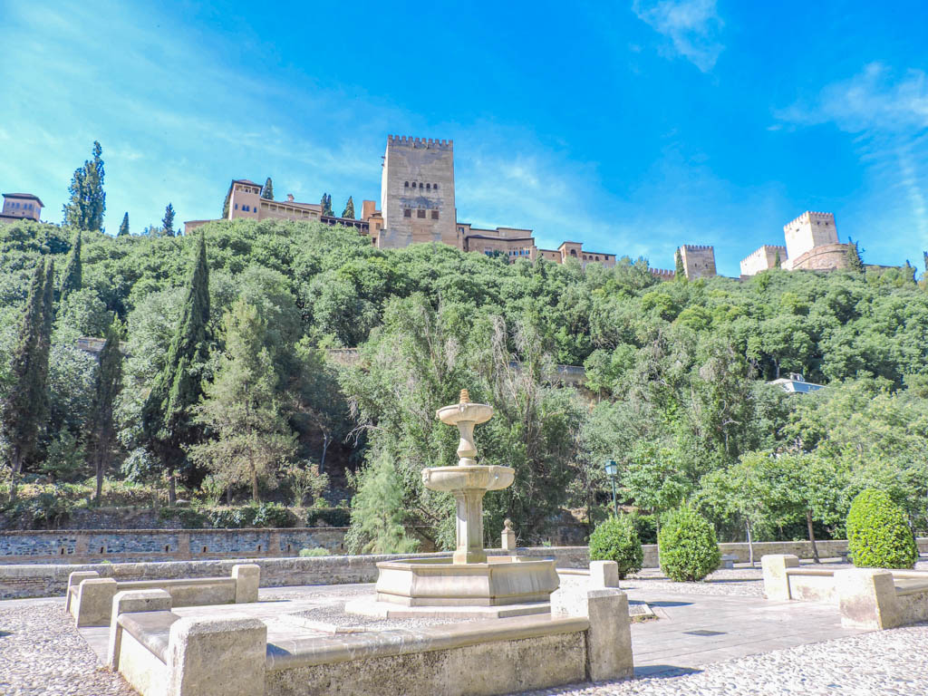 Blue skies over Granada Alhambra and green tress surrounding