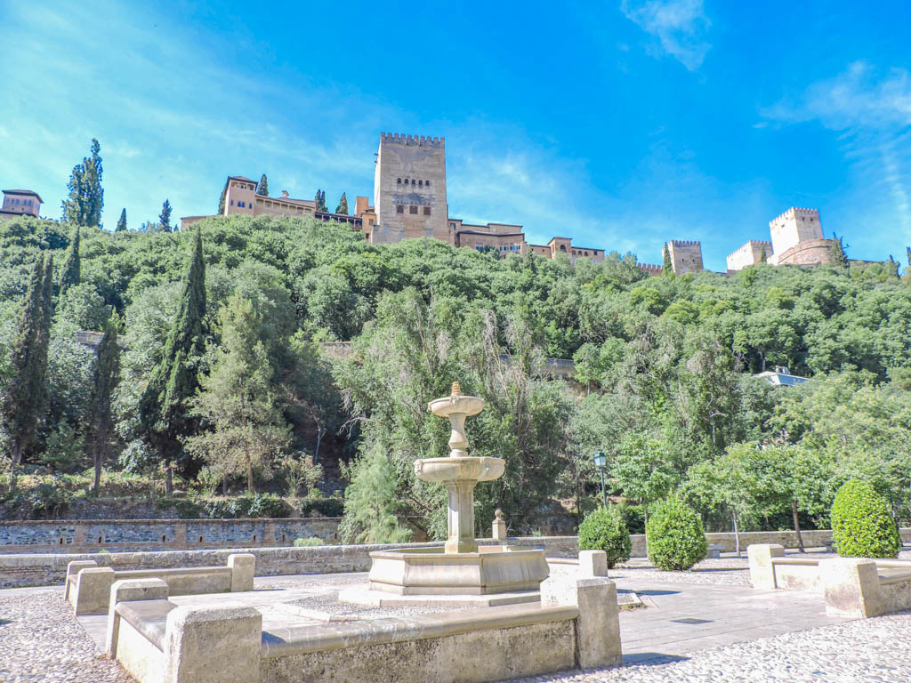 Blue skies over Granada Alhambra and green tress surrounding 