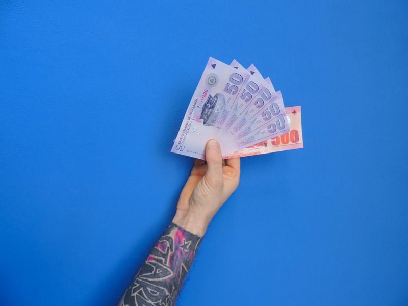 Hand holding foreign money against blue background