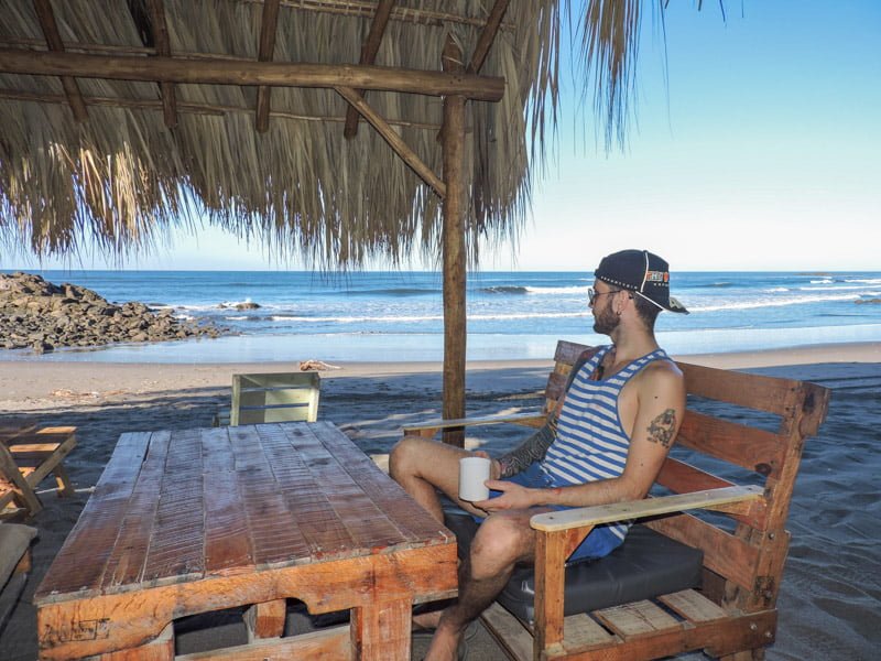 Man sits in chair looking at ocean from Simple Beach Lodge Las Penitas Nicaragua 