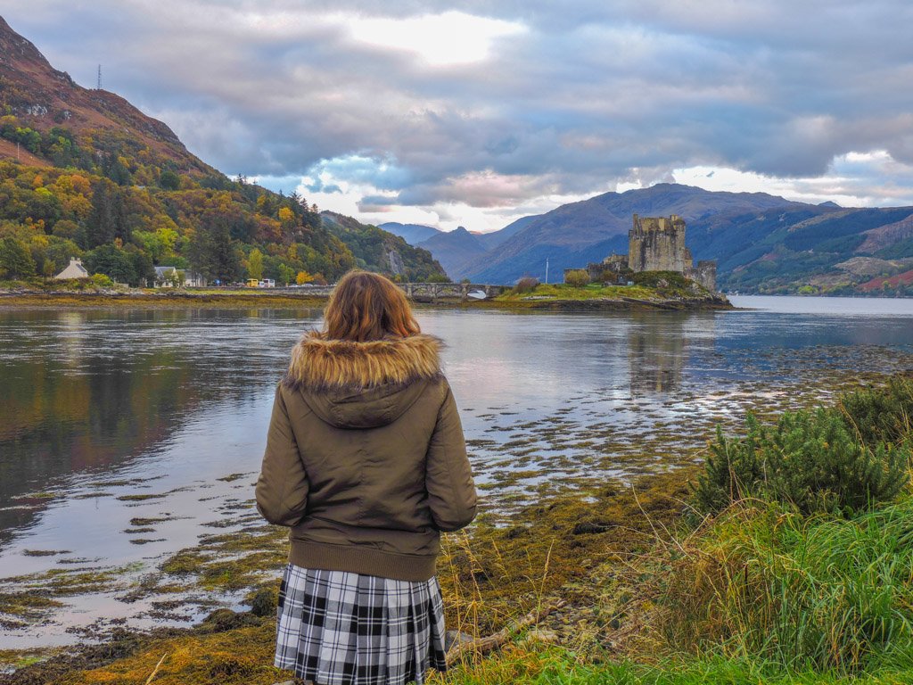 Woman in kilt in front of Eilean Donan Castle Scotland