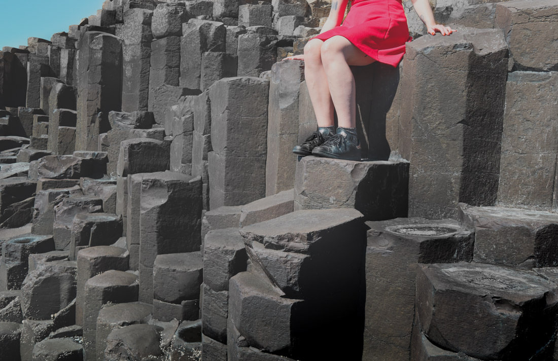 Photo of woman sitting on Giants Causeway rocks from