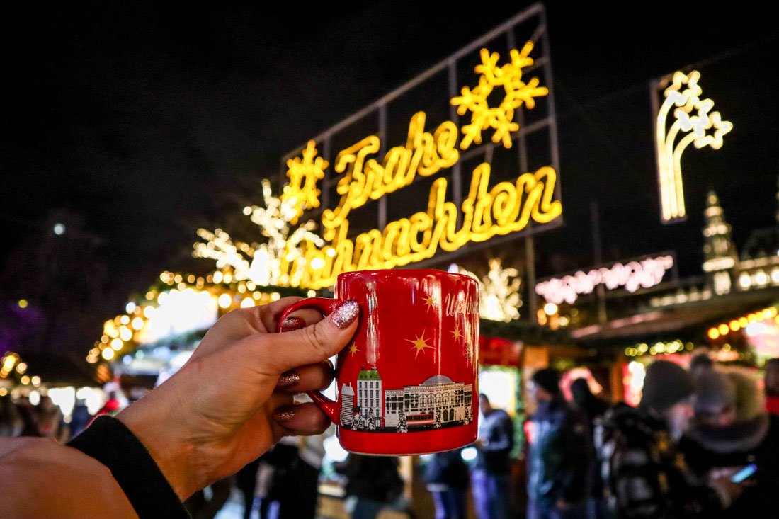 Hand holding festive mug in Vienna in Winter December at Christmas World on Rathausplatz