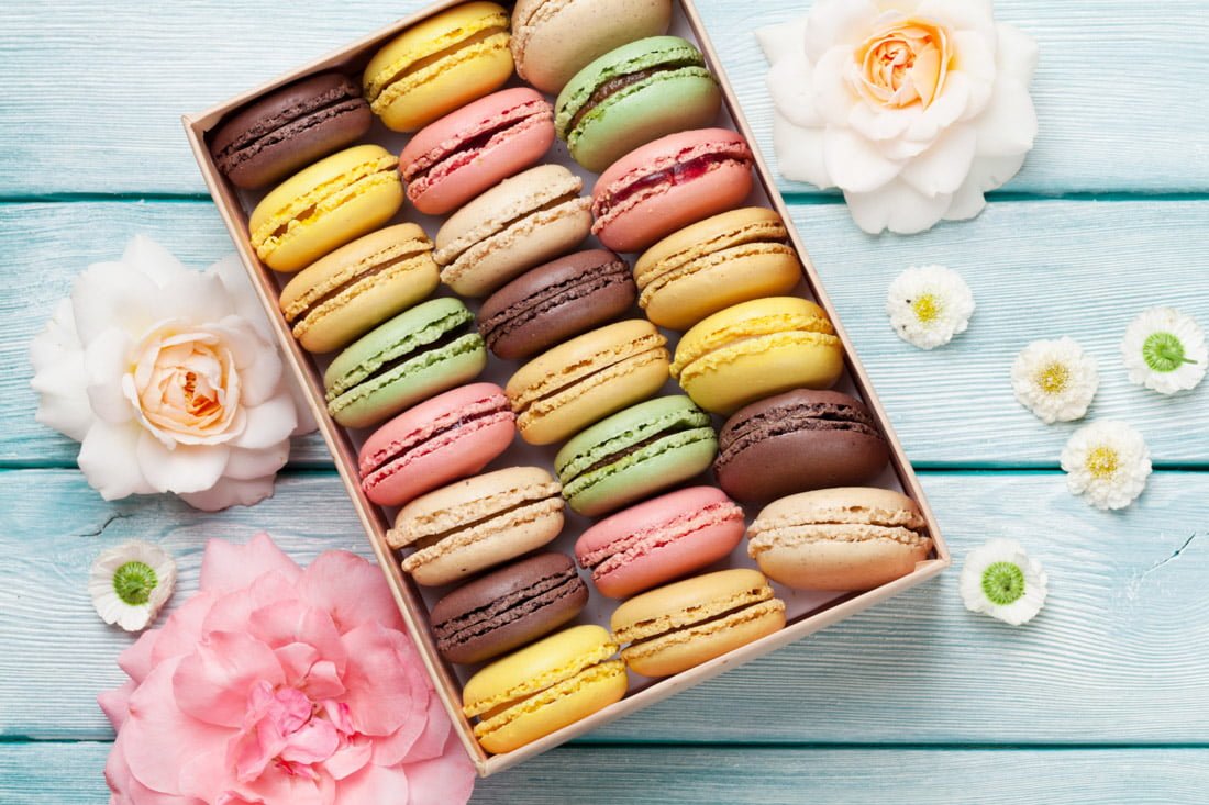 Colorful macarons in a box with flowers