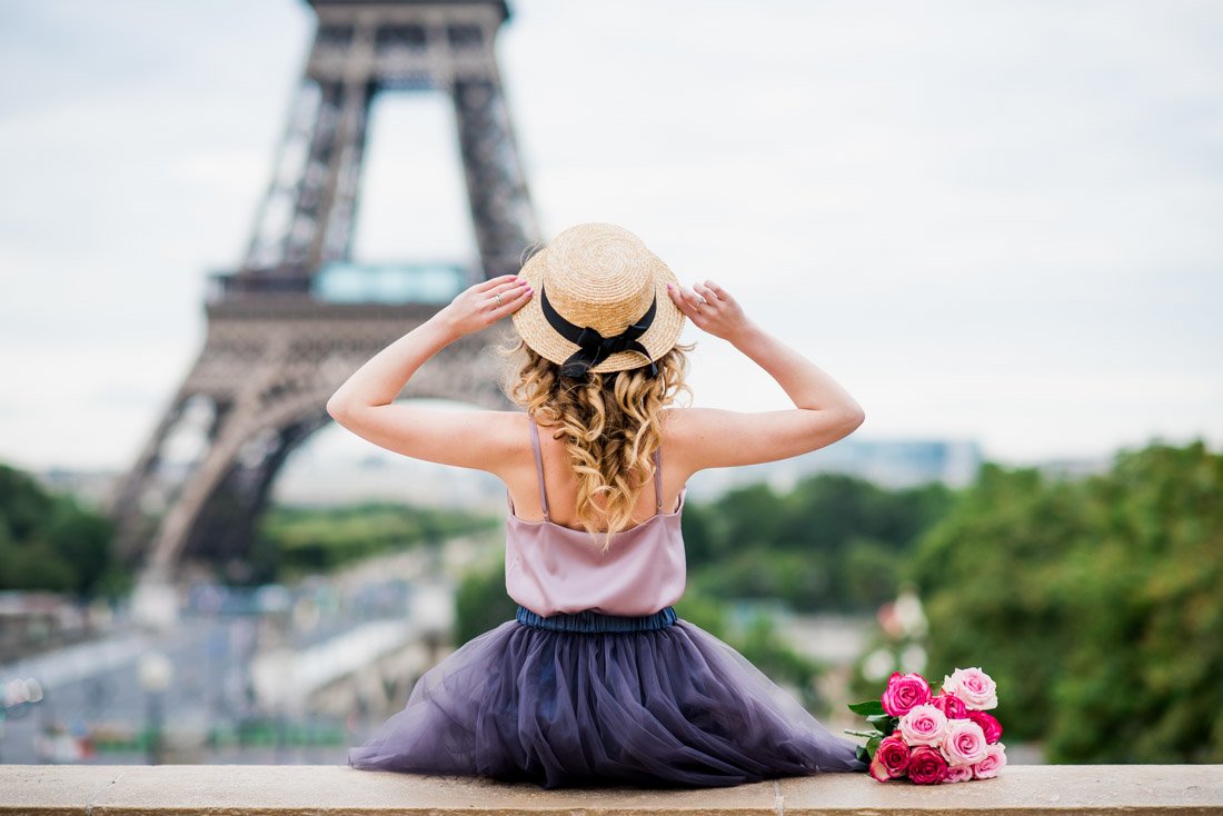 Woman holding hat with Eiffel Tower in background. Paris.