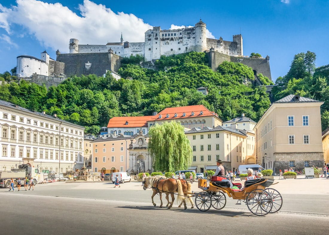 Salzburg with traditonal horse-drawn Fiaker carriage and famous Hohensalzburg Fortress