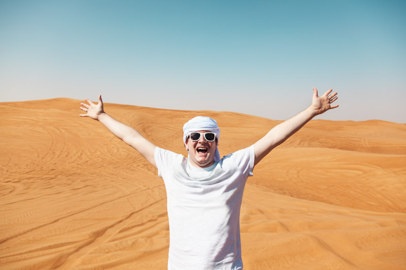 Happy man in Dubai desert wearing head scarf
