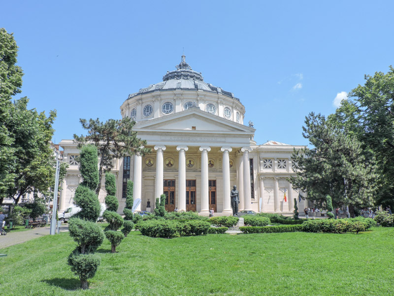 Romanian Athenaeum in Bucharest with green grass and blue skies
