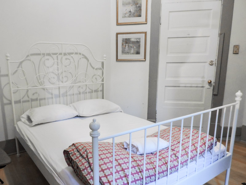 White metal bed in white room of St Claris Hostel Vancouver