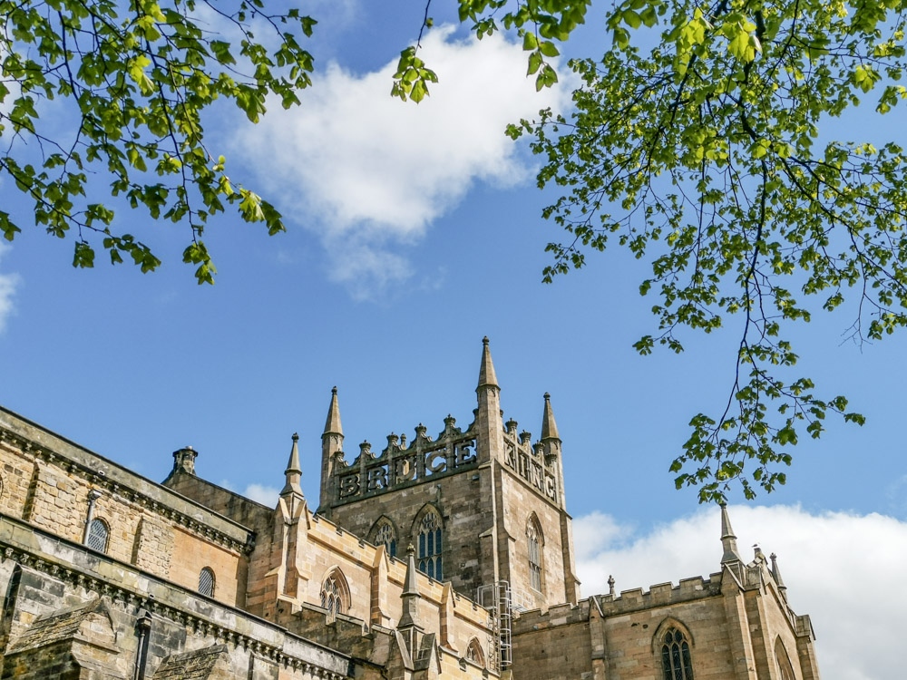 King Bruce carved into top of Dunfermline Abbey framed by tree in Fife, Scotland