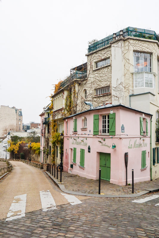 The famous restaurant, La Maison Rose in Paris. Pink building with green shutters and door at the corner of a Montmartre street. 