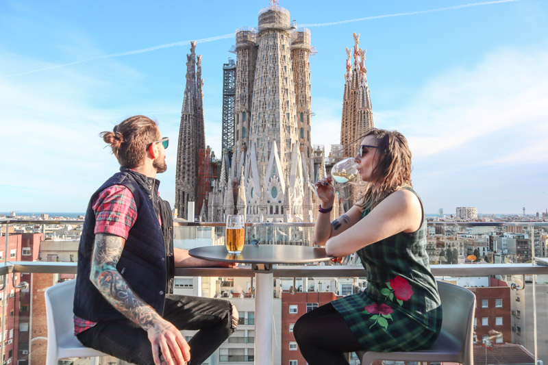 Couple having a drink at Ayre Hotel rooftop with Sagrada Familia in background