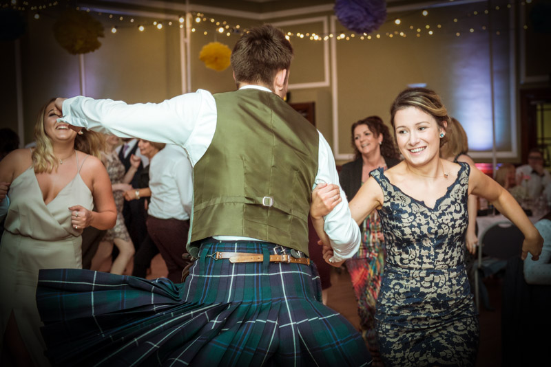 Scottish couple doing ceilidh dance man in a kilt