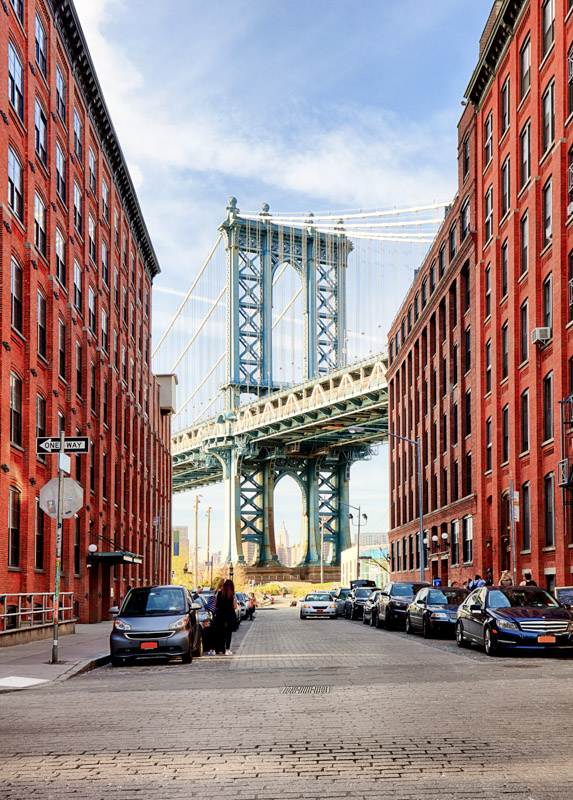 DUMBO view of Manhattan Bridge New York City with red stone buildings framing the bridge