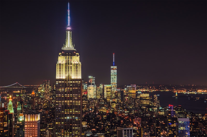 City skyline and Empire State Building at night in a dark NYC