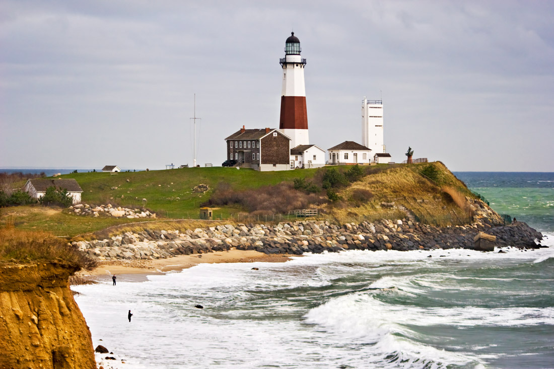 Red and white Montauk Point Lighthouse on cliff by ocean