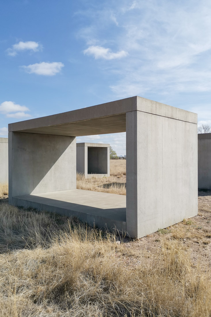 15 Untitled Works in Concrete in Marfa Texas - Two grey concrete hollow boxes on sandy ground with blue skies and shadows