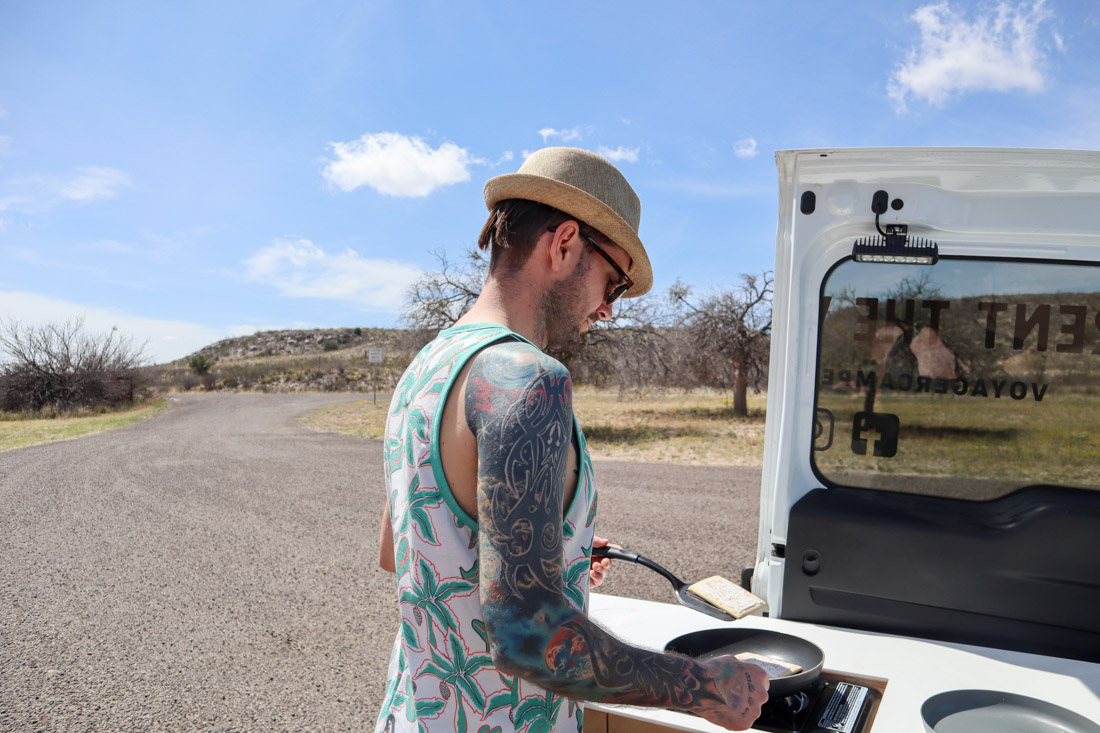 Man cooking at campervan on Texas road trip