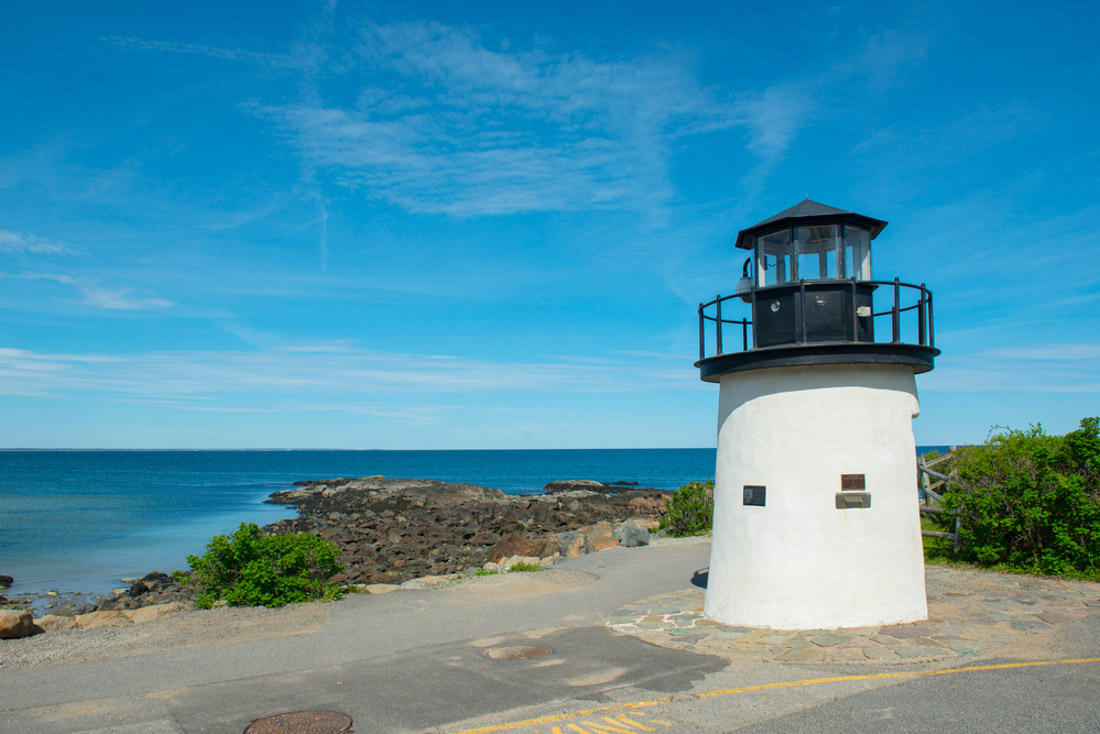 Lobster Point Lighthouse Maine Beach with blue skies