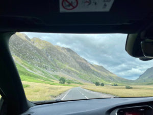 Glencoe on Scotland road trip sweeping green landscape view from front window of car