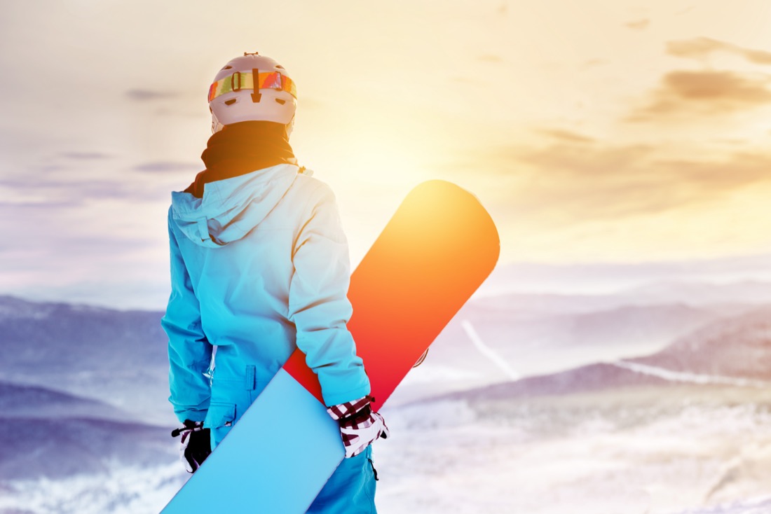 Ski boarder at sunset on snowy mountain