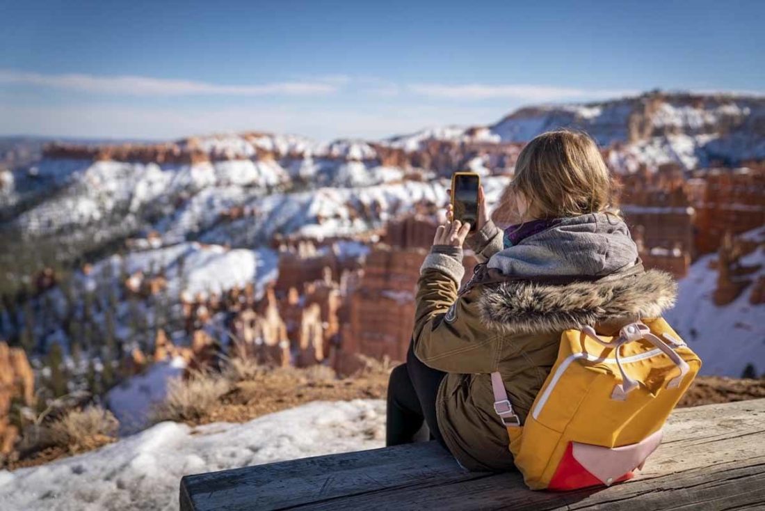 Woman sits looking over Bryce Canyon in Winter