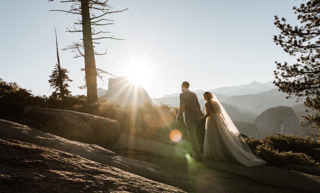 Bride and groom walk up hill at sunriseat Yosemite