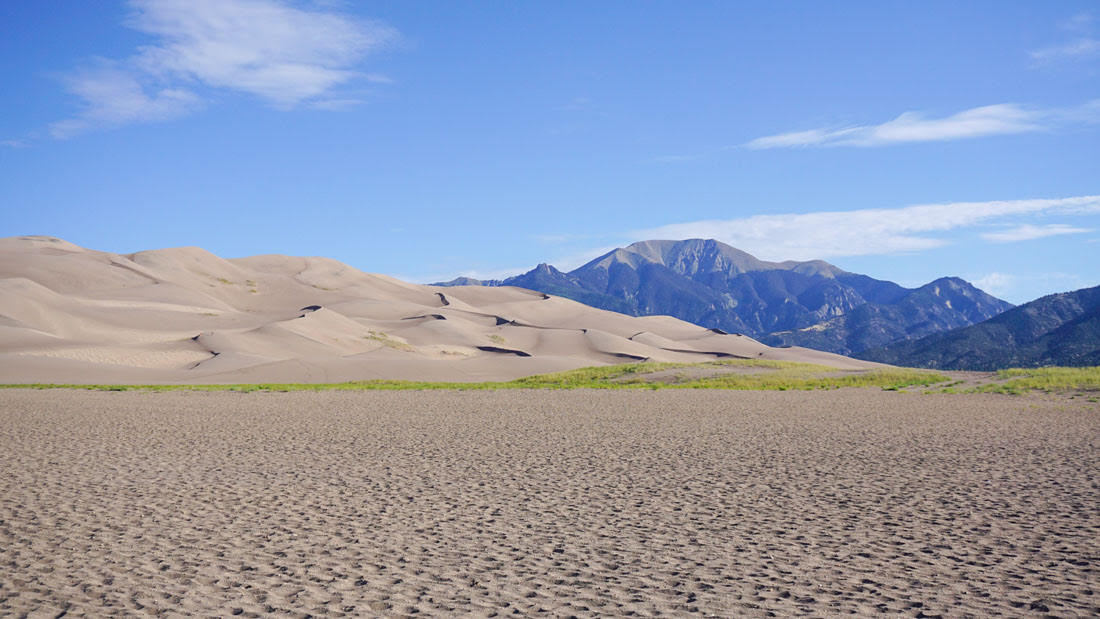 Light sand and blue skies with mountain in distance at Great Sands National Park