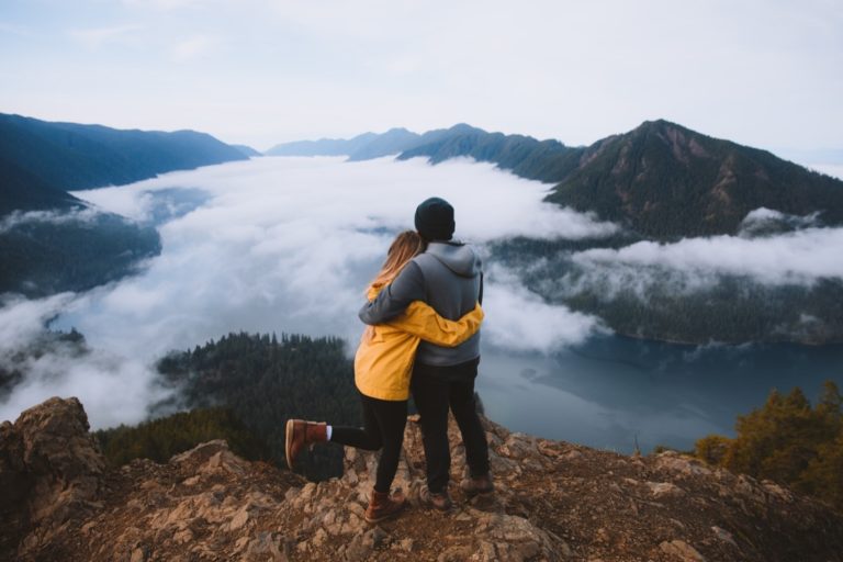 Couple cuddling at Olympic National Park with low hanging clouds