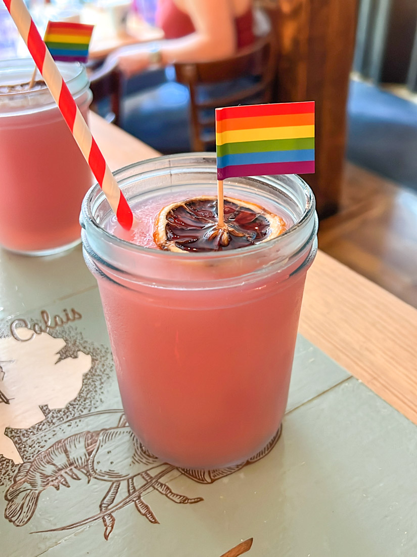 Red frozen cocktail in glass with rainbow flag