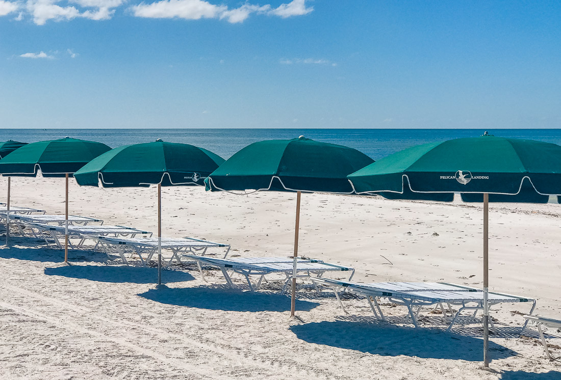 Beach umbrellas lined up at the shore in Naples Beach