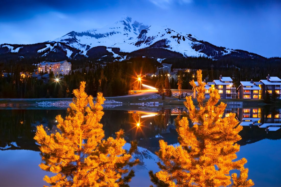 Big Sky Mountain Village ski resort in dusk with the view of Lone Mountain covered in snow