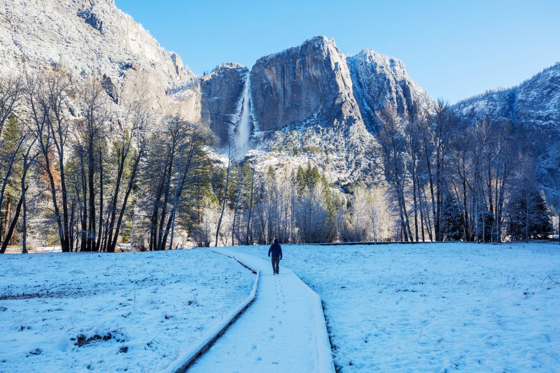 Snow on the ground and man walking at Yosemite National Park in winter