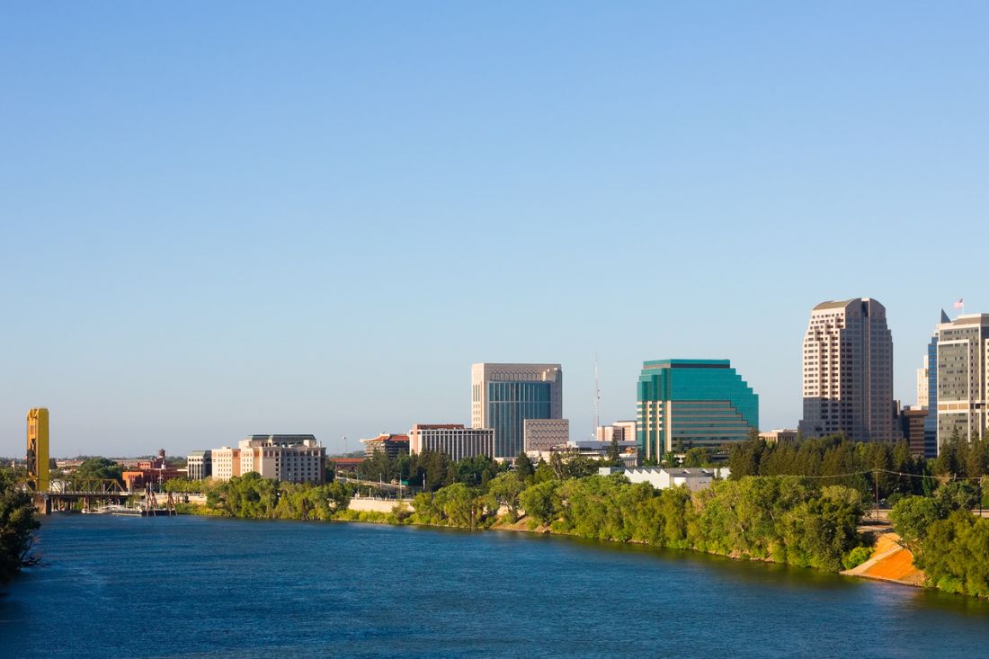 View of Sacramento's skyline with building and trees from the water.