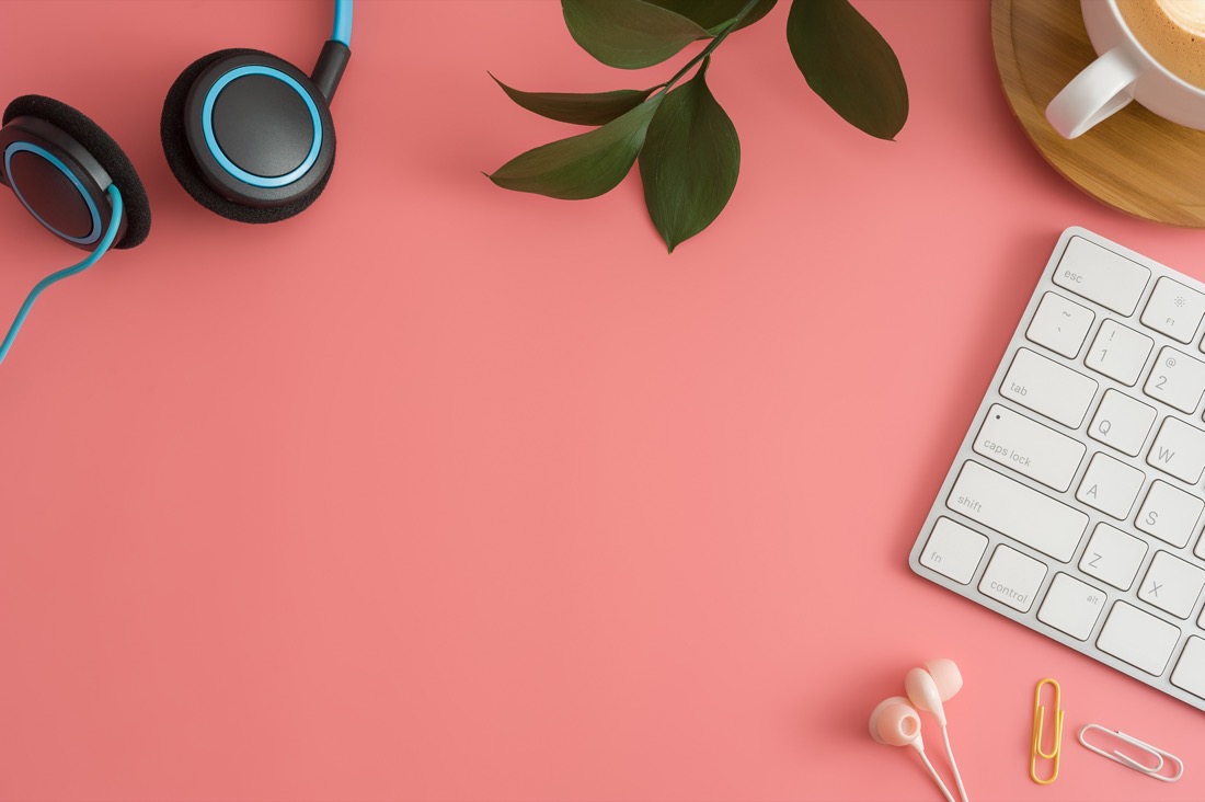 Earphones, plant and laptop keyboard on pink background