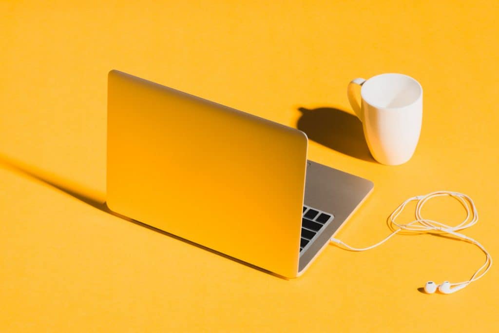 Laptop with mug on yellow background