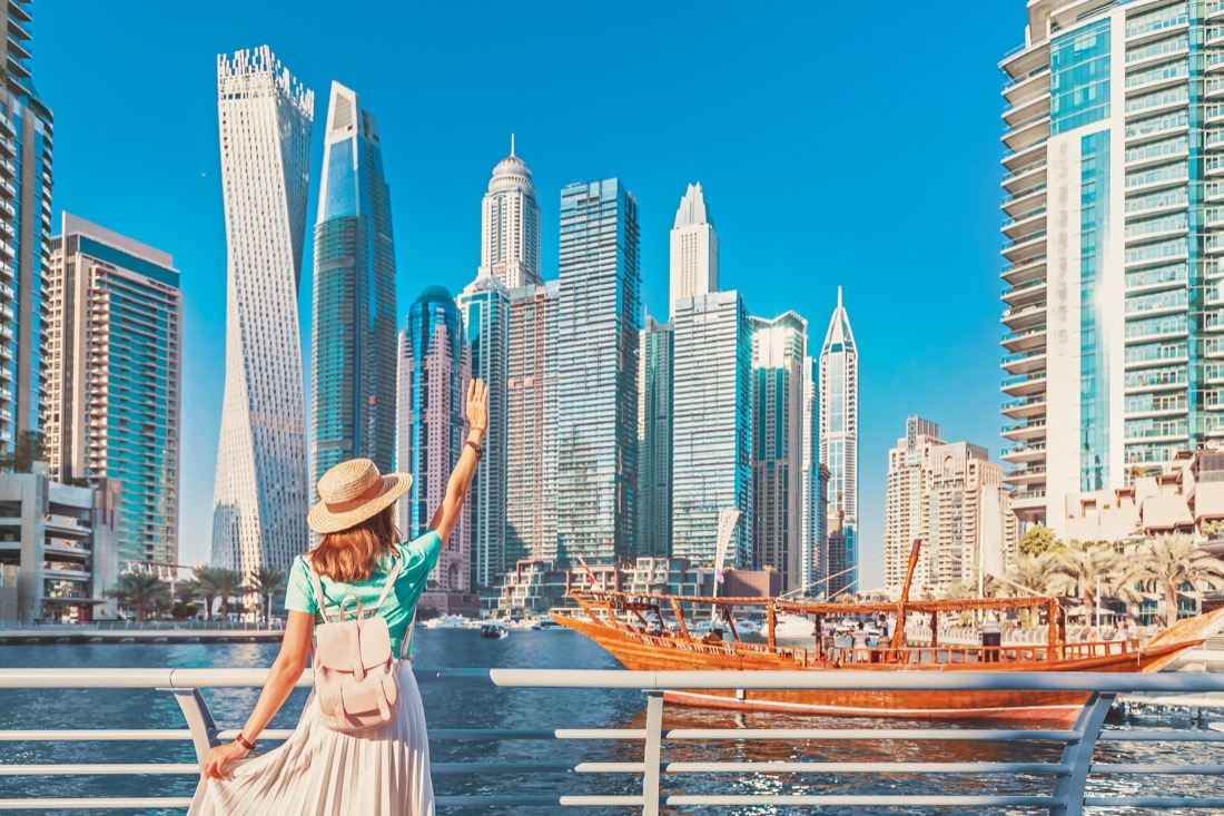 Cheerful traveler girl walking on a promenade in Dubai