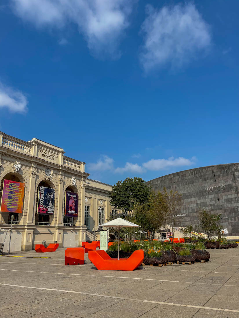 MuseumsQuartier historic and modern building and red chairs in Vienna Austria